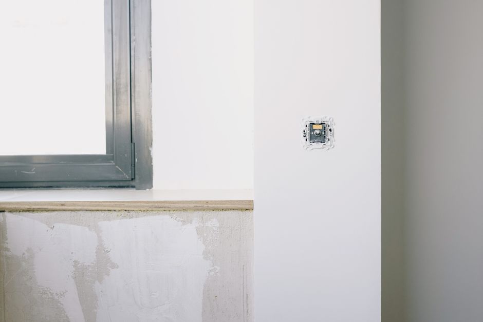 White window frame in a light interior wall beside a pane of clear glass