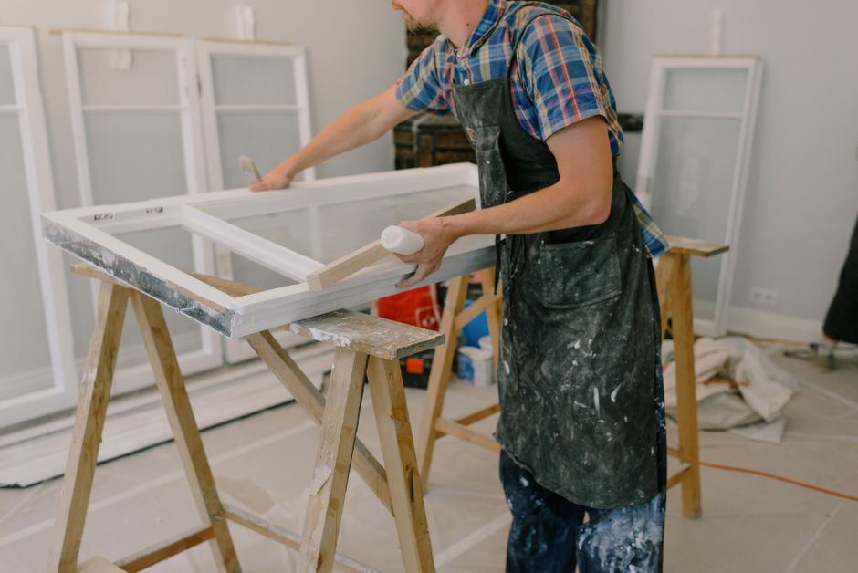 Installer in an apron standing beside a white framed window on a wooden workbench