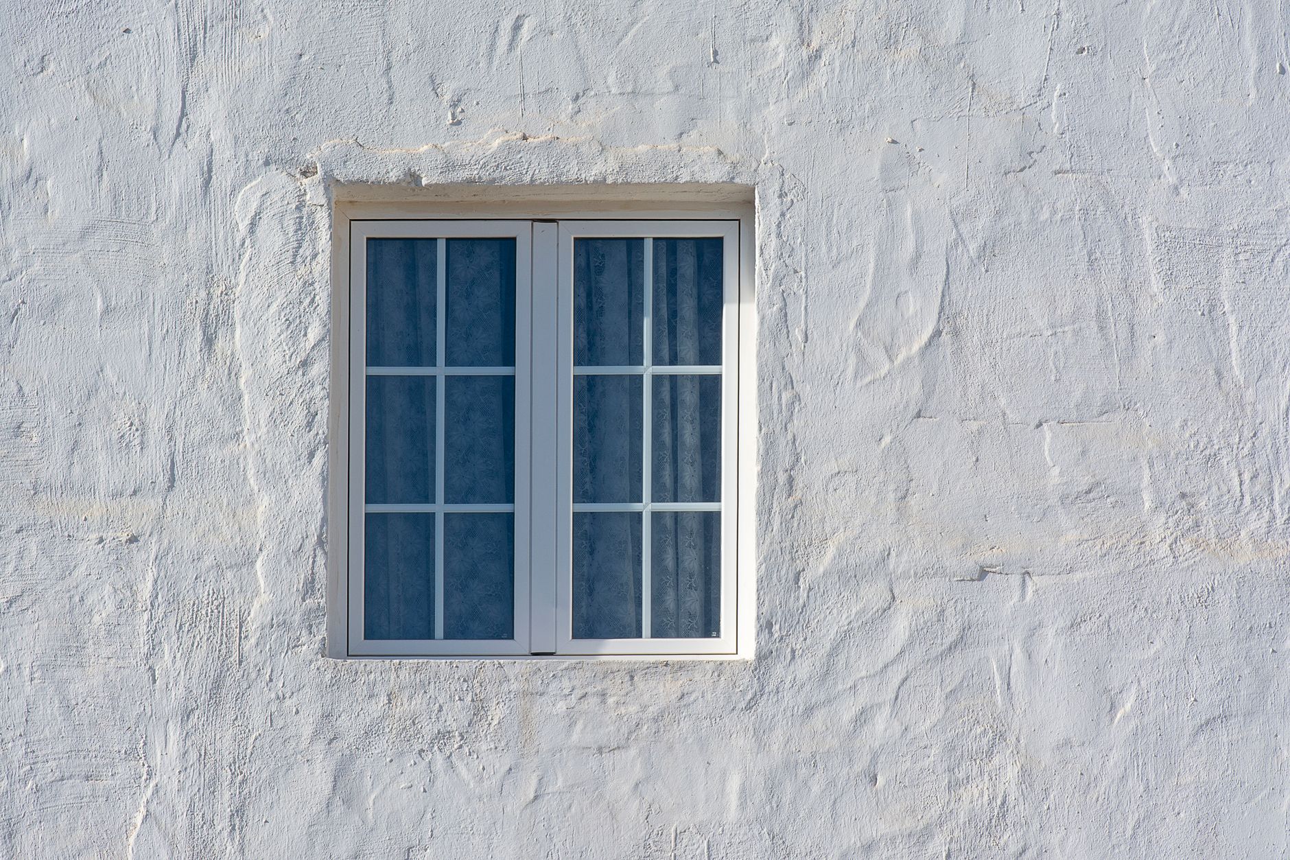 A whitewashed wall featuring a rustic window, captured in natural light in Riverside, CA